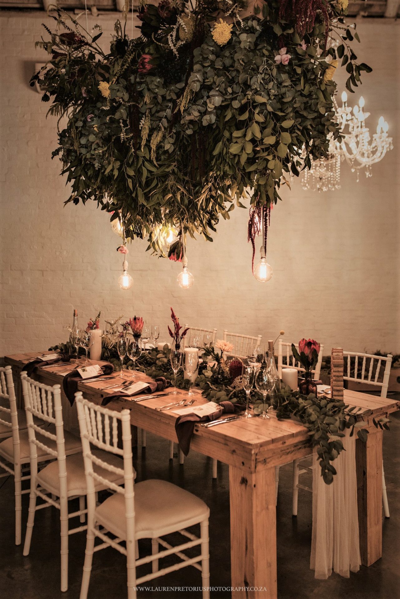 Greenery and Rosed Hanging From Ceilings With Bulb Lighting