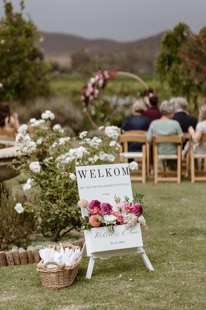 My Pretty Vintage in Paarl, Wedding Event Planners also offers beautiful Wedding Décor Hire. Minimalist Outdoor Ceremony Floral Bridal Arch. Welcome Board. Roses, Dahlias, scented Stock flowers Burgandy Purple Cream Blush.